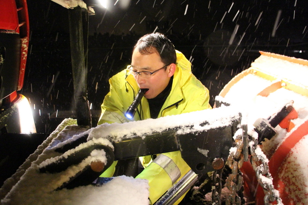 風雪中，馬巢公司夜班除雪隊員李夫勝正在調試除雪鏟大燈.jpg